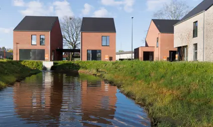 Vrijstaande nieuwbouwwoningen in de Matexi buurt in Haacht Scharent, met een waterpartij en enkele bomen.