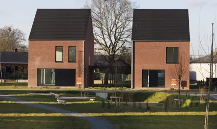Een rustige straat in een woonwijk met bomen en vrijstaande nieuwbouwhuizen